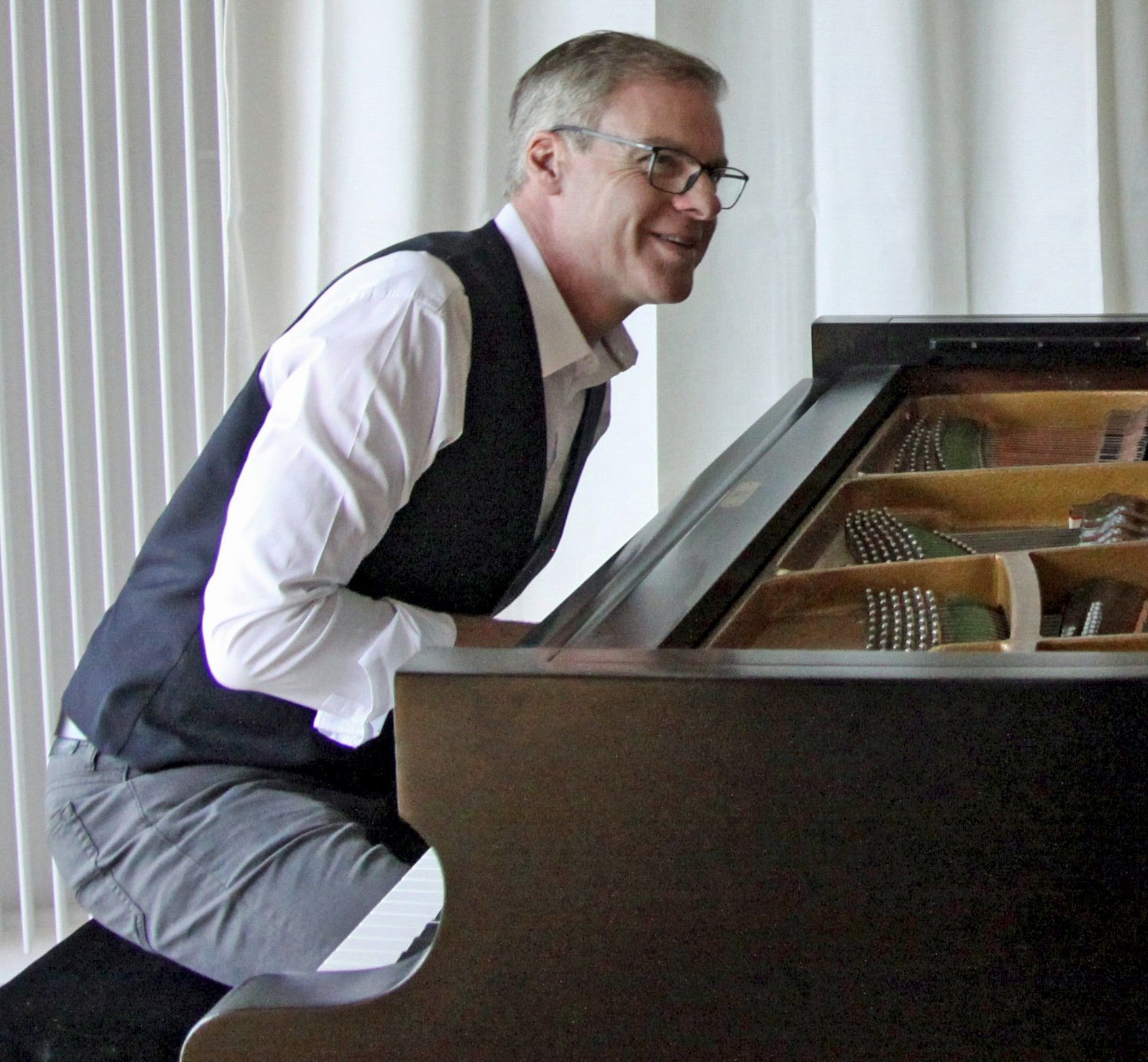 Le professeur de Double Croche, souriant, au piano à queue