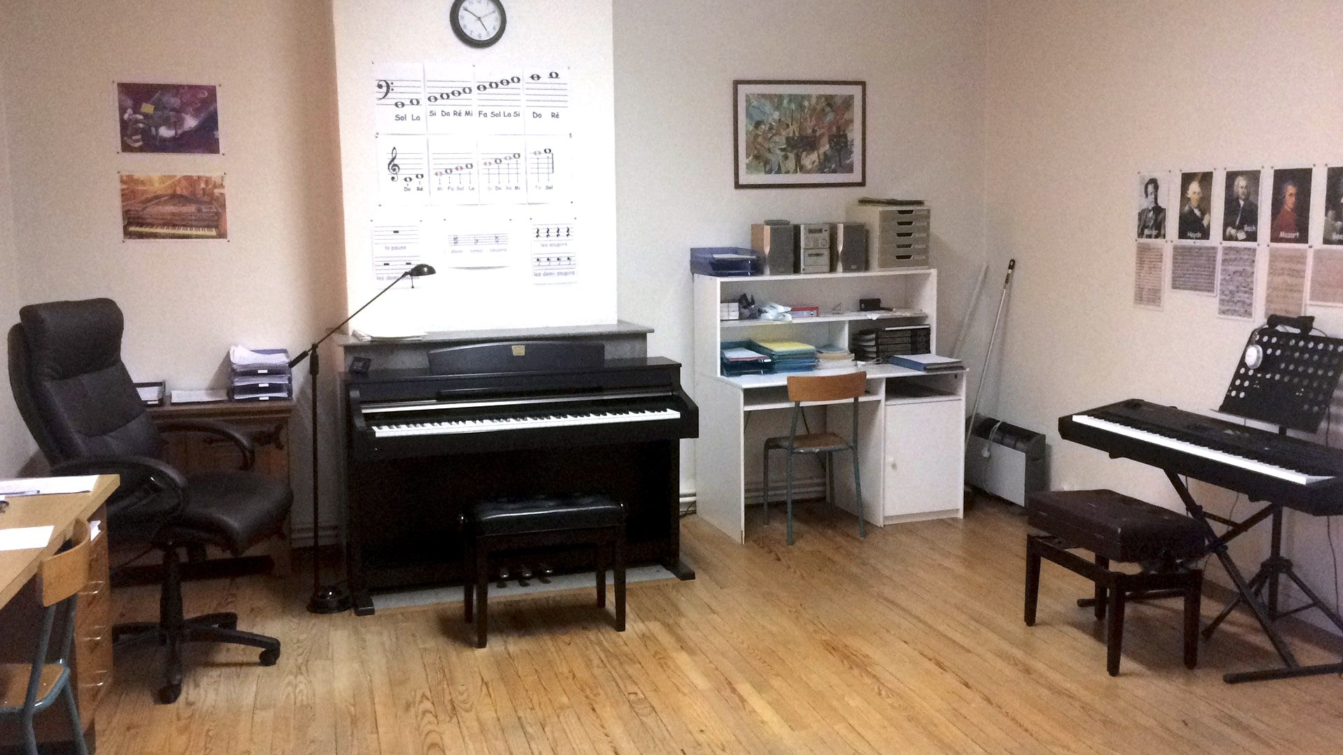 La salle de cours : piano numérique, clavier sur pied, partitions au mur et parquet